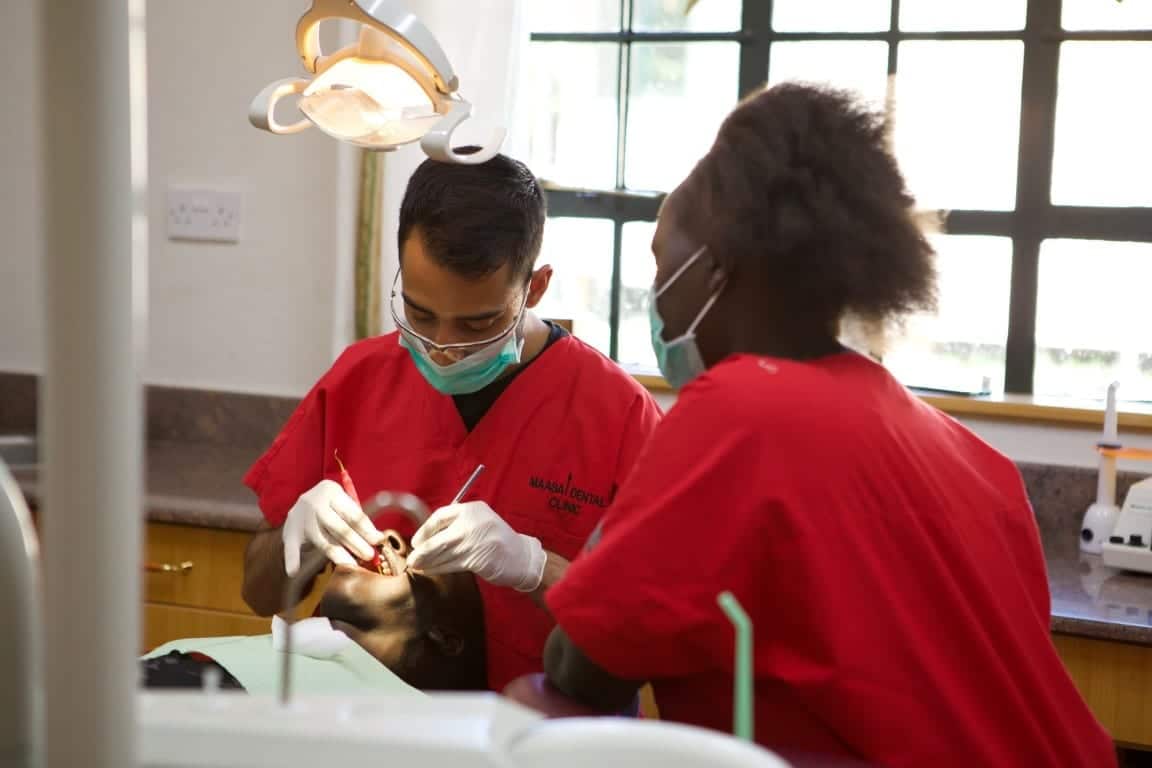Dentist cleaning teeth with assistant